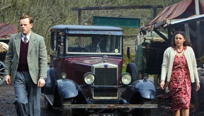 Picture shows: Tristan Farnon (Callum Woodhouse) and Florence Pandhi (Sophie Khan Levy) standing on either side of a 1930s car in a muddy yard
