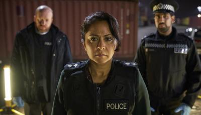 DI Ray in her police uniform looking serious with two officers standing behind her.