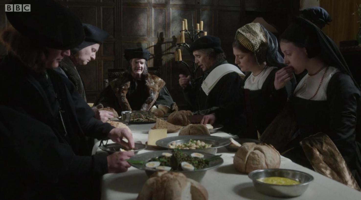Picture shows: Thomas Cromwell (Mark Rylance) at dinner with Sir Thomas More (Anton Lesser) and his family at a wooden table by candlelight.