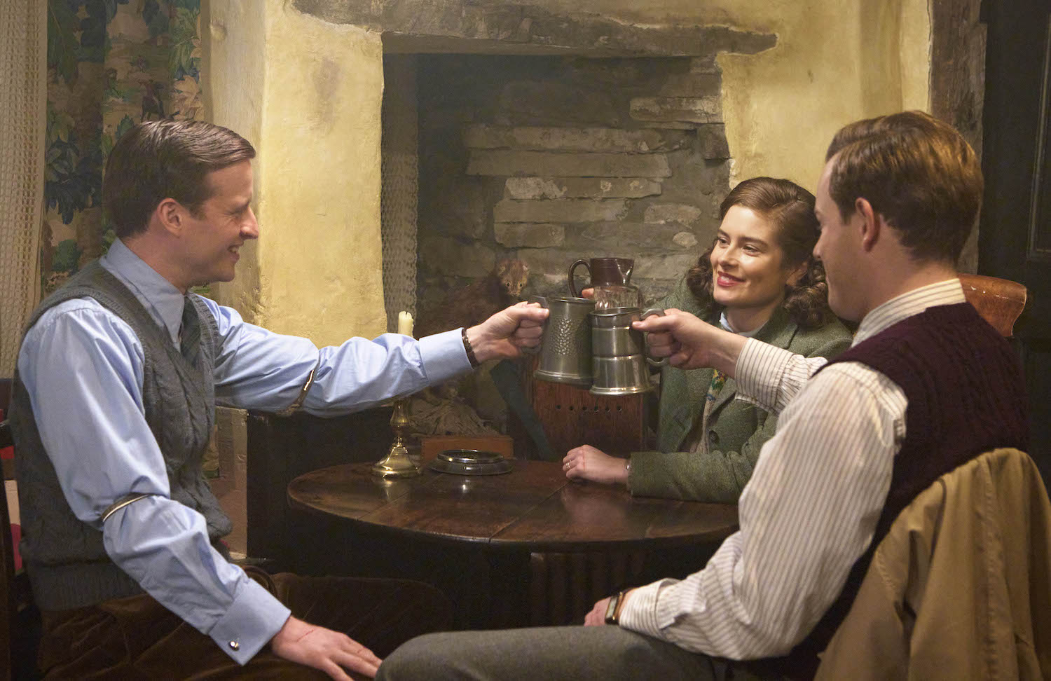 Picture shows: James (Nicholas Ralph), Helen (Rachel Shenton) and Tristan (Callum Woodhouse), seated at a table in the pub, raise a glass to celebrate their survival of Georgina the cat.