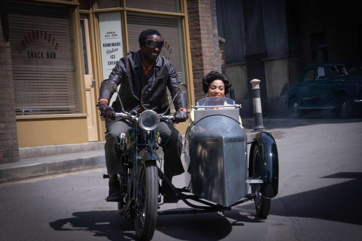 Picture shows Cyril (Zephryn Tate) and Lucille (Leonie Elliott) driving off to the airport. He's riding the motorcycle, with Lucille (Leonie Elliot) in the sidecar.