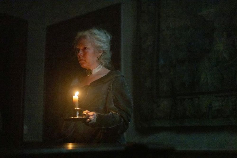 Olivia Colman as Miss Havisham walking through a darkened house with only a candle to light her way in 'Great Expectations' Episode 6