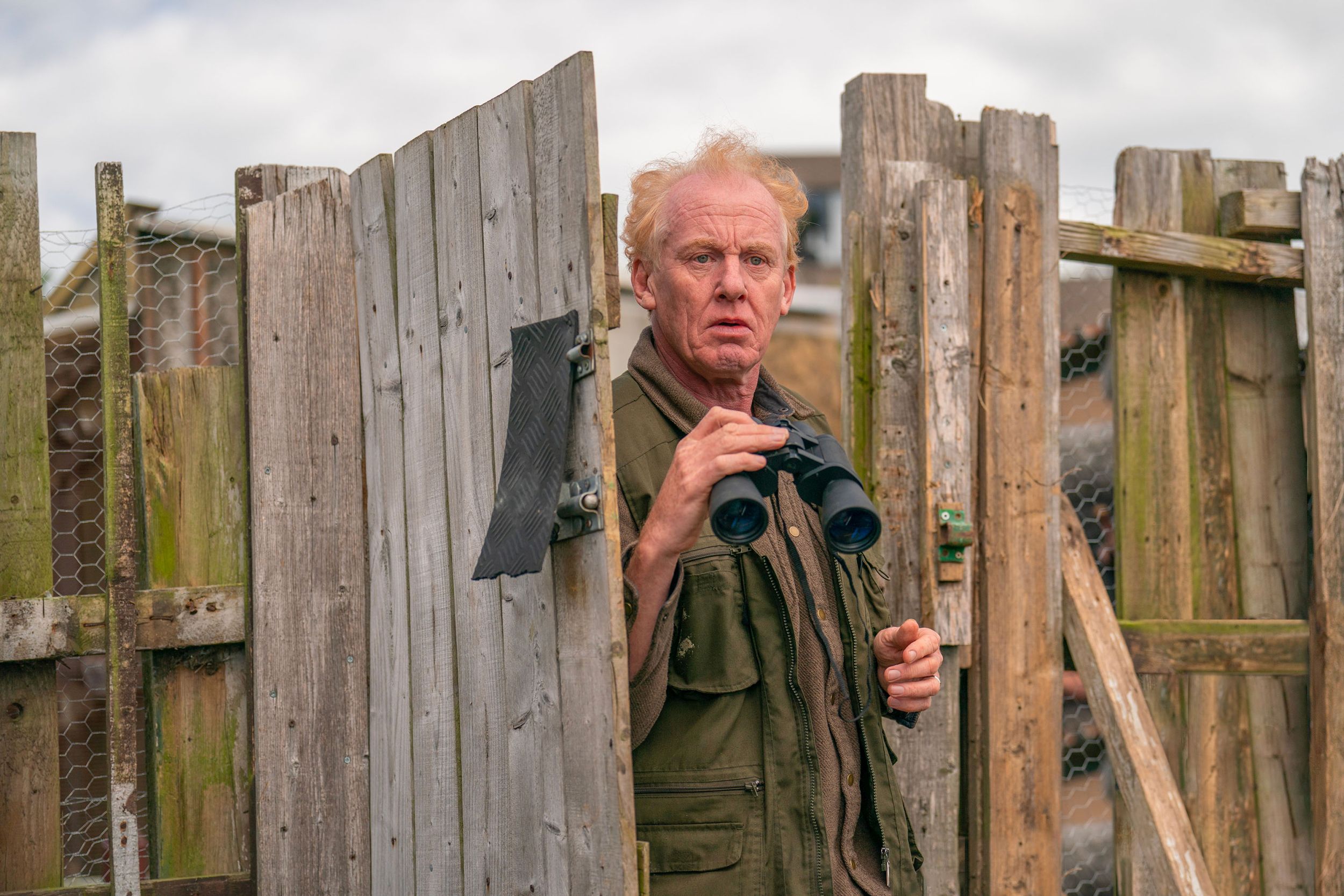 Steve Huison as Lomper exiting out his back gate with binoculars in The Full Monty 