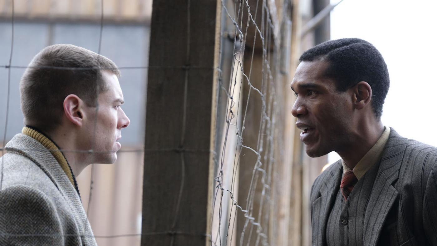 Picture shows: Webster O’Connor (Brian J. Smith) and Albert Fallou (Parker Sawyers) quarrel, divided by a wire fence.