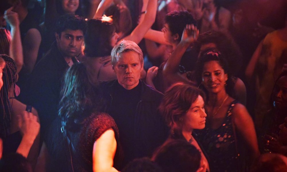 Eddie Suleman (Azan Ahmed), Van Der Valk (Marc Warren), and Lucienne Hassell (Mamie McCoy) make their way through a crowd of dancers at the nightclub.
