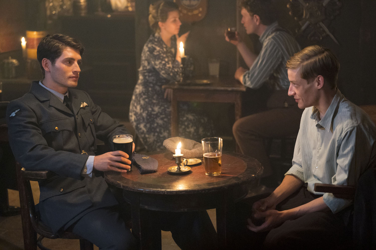 Picture shows: A reunion in a candle-lit pub between Grzegorz (Mateusz Więcławek) and David (Gregg Sulkin), who's made it safely home from occupied France.