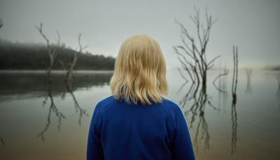 Julia Savage as Amy stares at a lake in Hulu's The Clearing