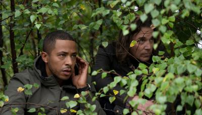 Ukweli Roach as DS Tyrone Clarke Jamie Sives as DS Michael McAndrews hide in the bushes in Annika Season 2