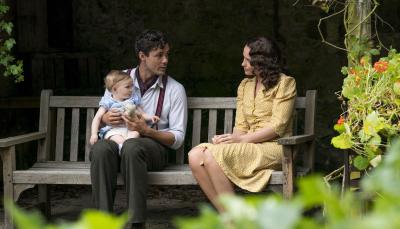 Picture shows: Harry (Jonah Hauer-King) and Lois (Julia Brown) sit in on a garden bench surrounded by flowers and greenery. Harry is holding his daughter.