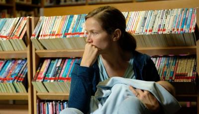 Picture shows: Emily (Jessica Hynes) sits against a bookshelf in the library with her baby in her arms. She looks sad and defeated.