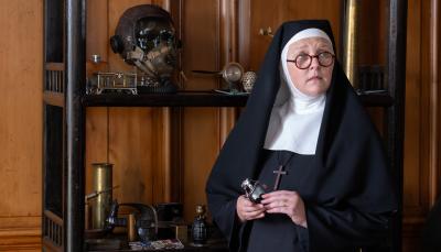 Lorna Watson as Sister Boniface next to a shelf of murder weapons in Sister Boniface Mysteries Season 3