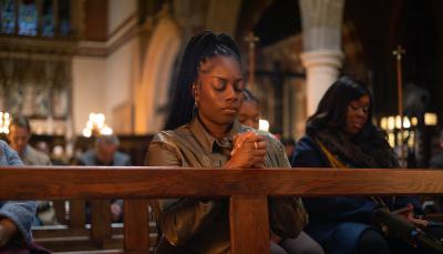 Dionne Brown as Queenie Jenkins, on her knees praying in 'Queenie'