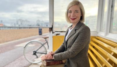 Lucy Worsley in Portsmouth Beach Shelter with book in hand in 'Holmes vs Doyle'