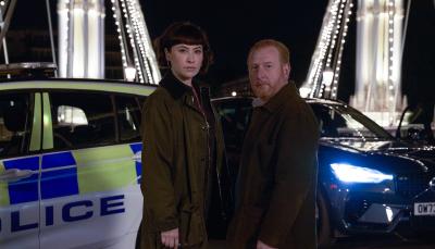 Picture shows: DI Max Arnold (Adrian Scarborough) and DS Layla Walsh (Vanessa Emme) on the Chelsea Bridge with police cars in the background.