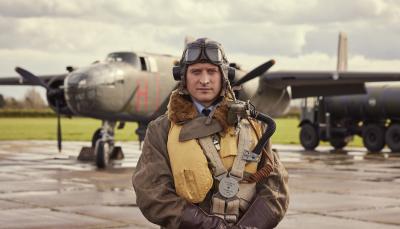 Picture shows: Nicholas Ralph in flying gear on an airfield with planes behind him.