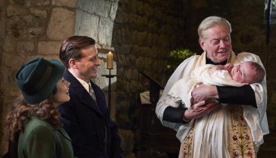 Picture shows: Baby Jimmy's christening. Helen Herriott (Rachel Shenton) and James Herriot (Nicholas Ralph) watch as the Vicar (Mark Chatterton) prepares to baptize their baby son.