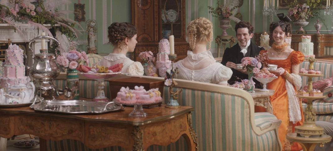 Picture shows: Harriet (Mia Goth) and Emma (Ana Taylor-Joy) host Mr. Elton (Josh O'Connor) and Mrs. Elton (Tanya Reynolds) at a tea party where there are many pastel-colored cakes and desserts.