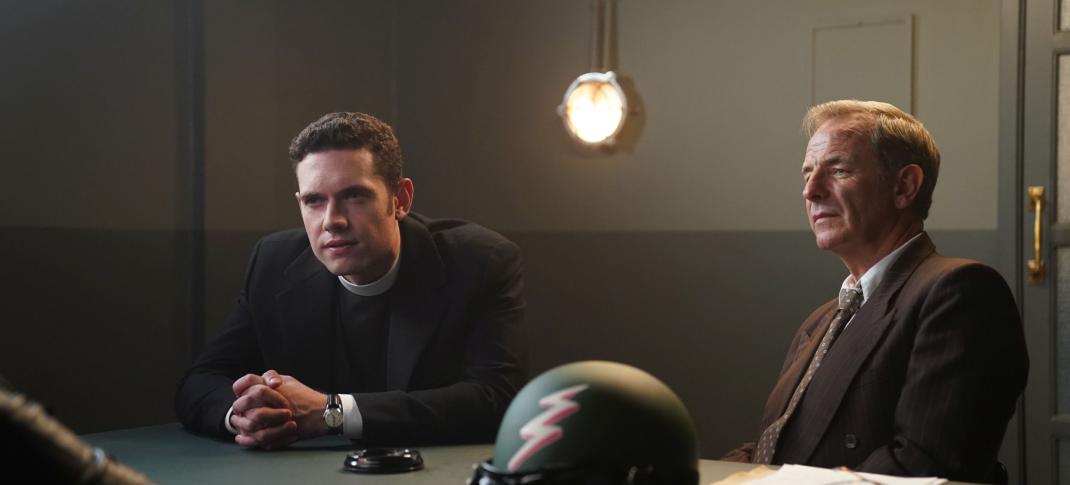 Tom Brittney as Will Davenport and Robson Green as Geordie Keating sit across from a suspect during an interrogation in 'Grantchester' Season 8