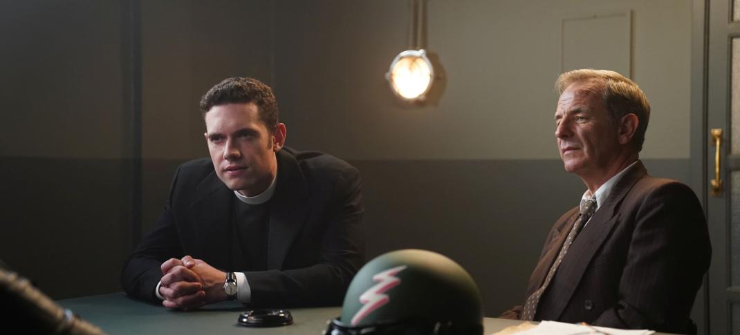 Tom Brittney as Will Davenport and Robson Green as Geordie Keating sit across from a suspect during an interrogation in 'Grantchester' Season 8  