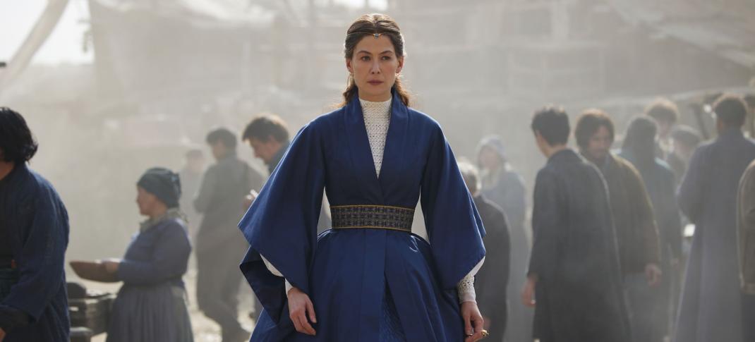 Rosamund Pike as Aes Sedai Moiraine Damodred walking through a not-so-nice part of the city in The Wheel of Time Season 2