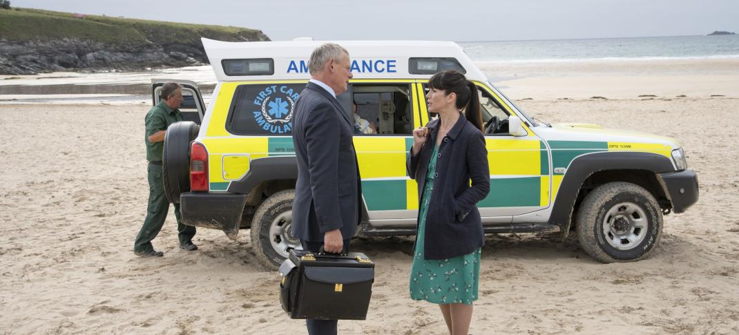 Martin Clunes as Dr. Martin, Caroline Catz as Louisa stand on the beach in front of an ambulance in Doc Martin Season 9