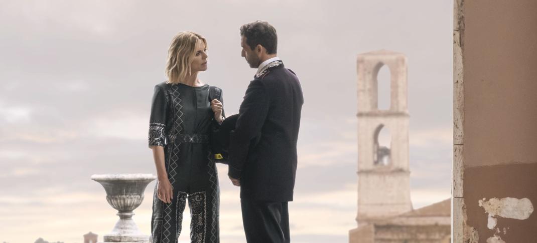 Emilia Fox as Sylvia Fox and Giovanni Cirfiera as Capitano Riva stand on a balcony in Italy in Signora Volpe Season 1