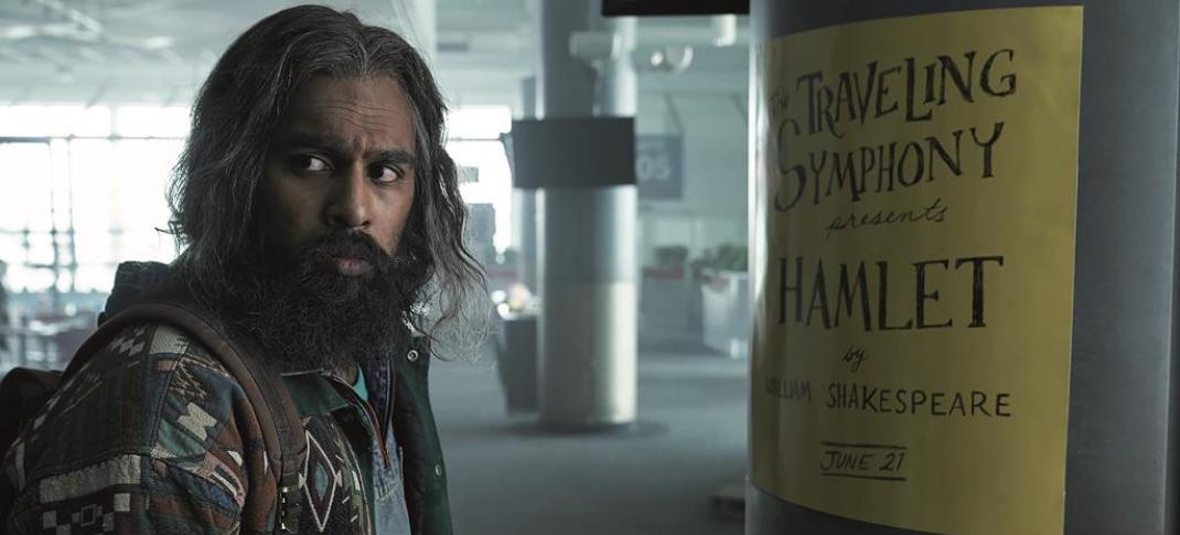 Himesh Patel as Jeevan Chaudhary in front of a Hamlet poster in 'Station Eleven'