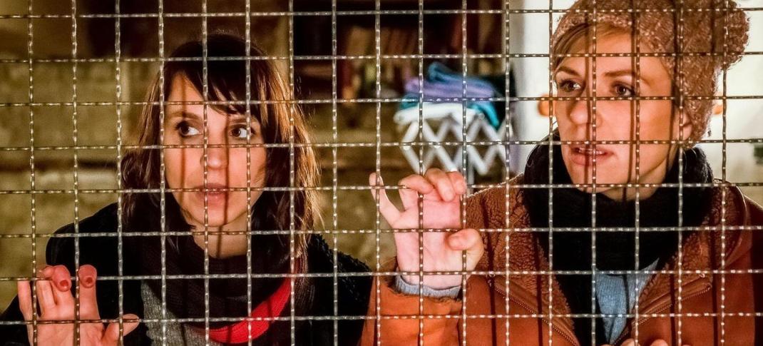 Caroline Erikson as Luna Kunath and Katrin Jaehne as Sophie Pohlmann are behind a wire fence in the German series SOKO Potsdam, renamed Luna + Sophie for Walter Presents