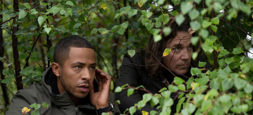 Ukweli Roach as DS Tyrone Clarke Jamie Sives as DS Michael McAndrews hide in the bushes in Annika Season 2
