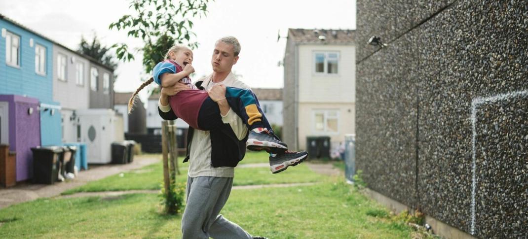 Lola Campbell as Georgie and Harris Dickinson as her dad Jason dancing her around the yard in 'Scrapper'