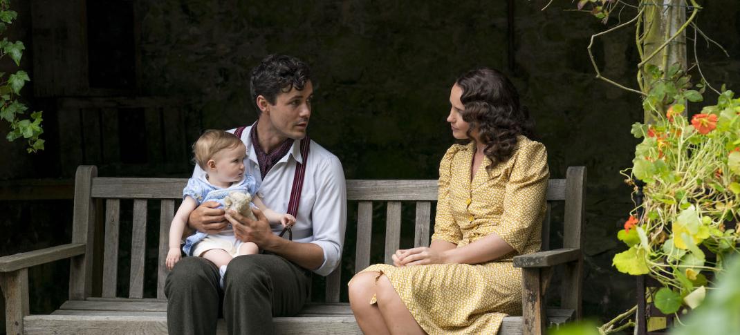 Picture shows: Harry (Jonah Hauer-King) and Lois (Julia Brown) sit in on a garden bench surrounded by flowers and greenery. Harry is holding his daughter.