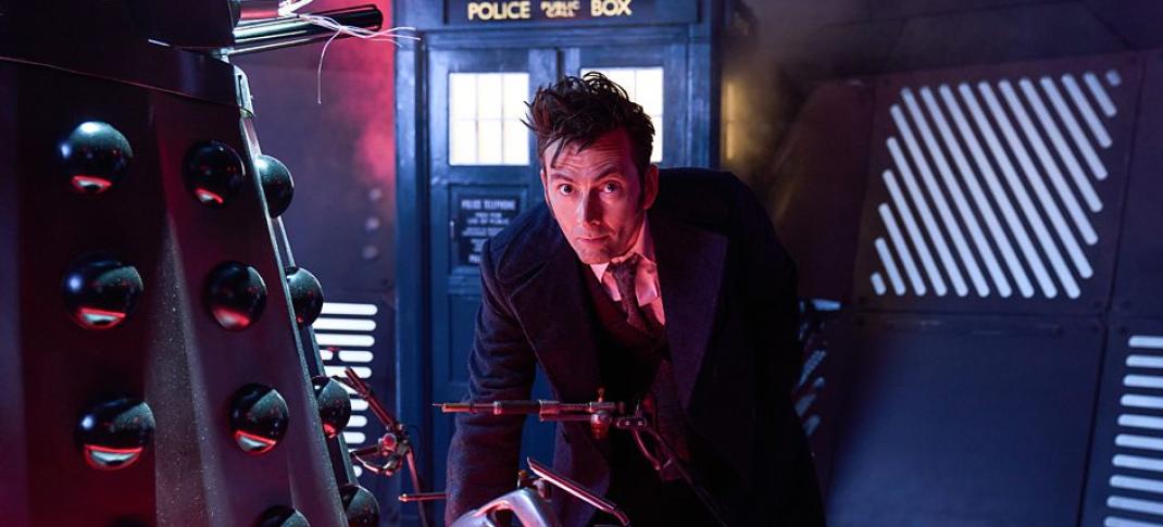 David Tennant stands by a Dalek with the TARDIS in the background