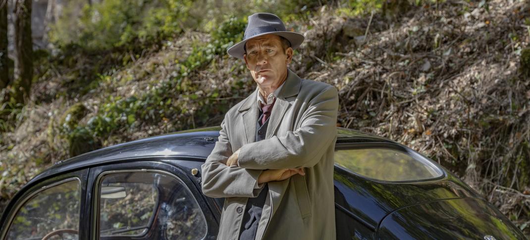 Clive Owen as Sam Spade in full Sam Spade regalia leaning on a total Sam Spade car on a hill in 'Monsieur Spade'