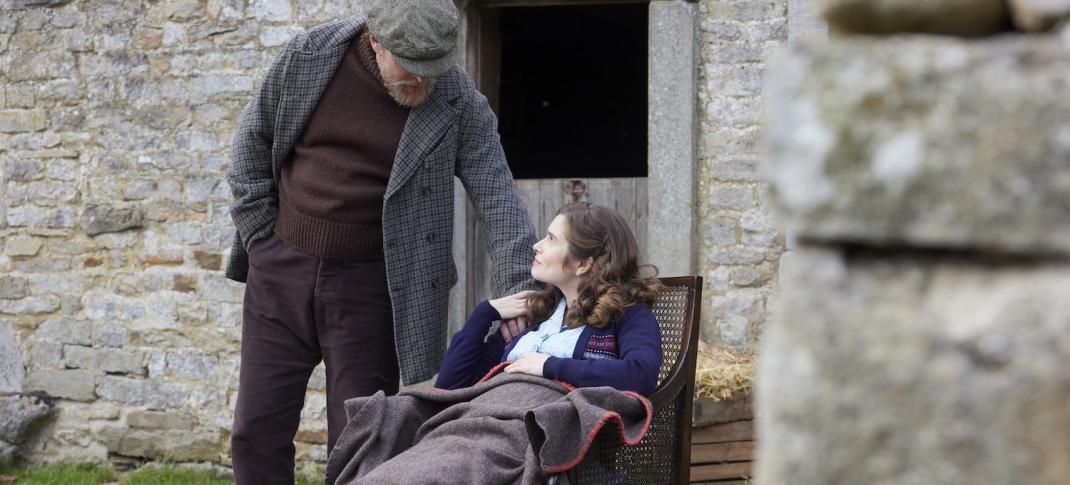 Picture shows: Richard Alderson (Tony Pitts) fusses over his pregnant daughter Helen Herriot (Rachel Shenton). She's sitting in a chair in a sunny farmyard wrapped in a blanket.