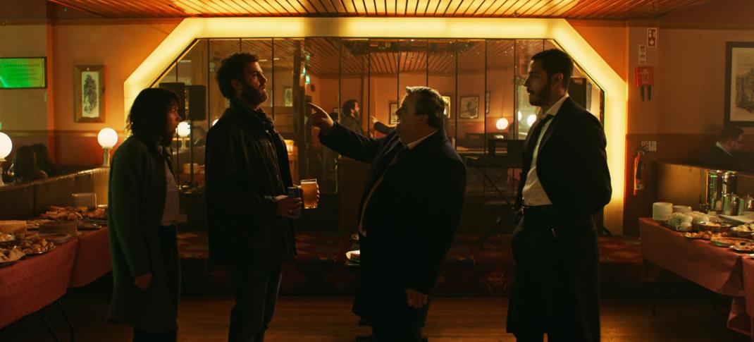 Ruth Wilson as Lorna, Mark Huberman as Michael, Simon Delaney as Massey, and Daryl McCormack as Colman confront each other at the bar in The Woman in the Wall