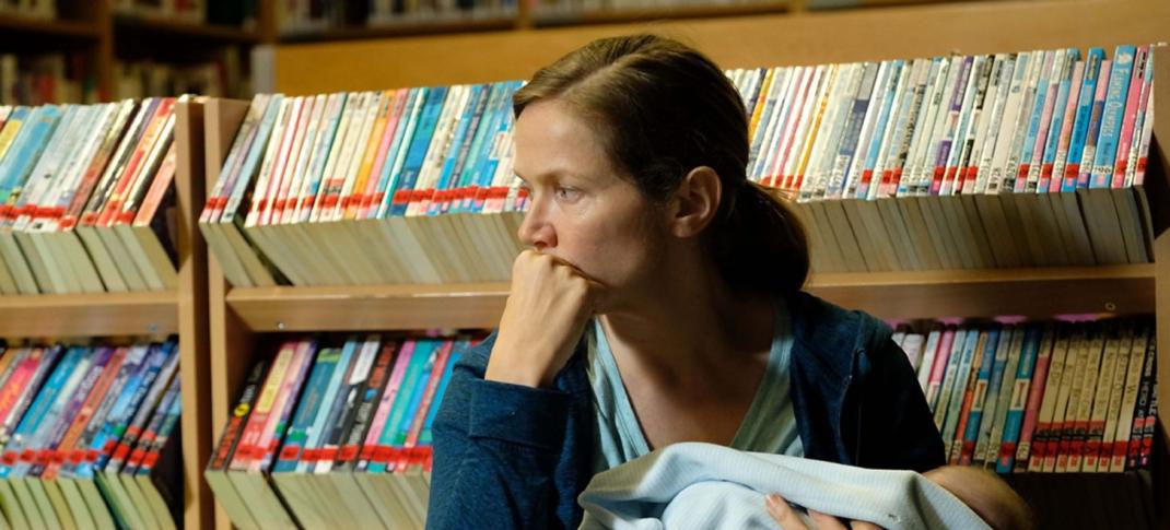 Picture shows: Emily (Jessica Hynes) sits against a bookshelf in the library with her baby in her arms. She looks sad and defeated.