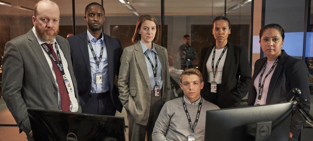 Steve Oram as DS Clive Bottomley, Peter Bankole as DS Kwesi Edmund, Gemma Whelan as DCI Kerry Henderson, Sam Baker-Jones as DC Liam Payne, Witney White as DC Charlene Ellis, and Parminder Nagra as DI Rachita Ray pose around a desk in the office in 'D.I. Ray' Season 2