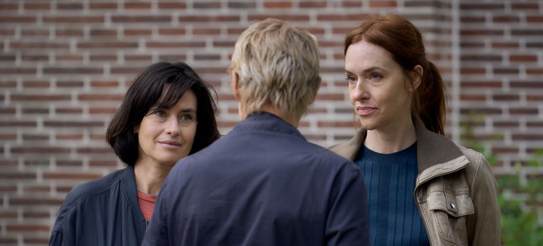Maimie McCoy and Kim Reidle as Lucienne and Kalie, ganging up on March Warren as Van der Valk in 'Van der Valk' Season 4