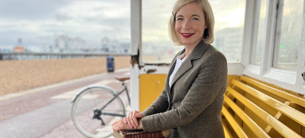 Lucy Worsley in Portsmouth Beach Shelter with book in hand in 'Holmes vs Doyle'