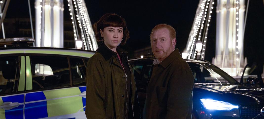 Picture shows: DI Max Arnold (Adrian Scarborough) and DS Layla Walsh (Vanessa Emme) on the Chelsea Bridge with police cars in the background.
