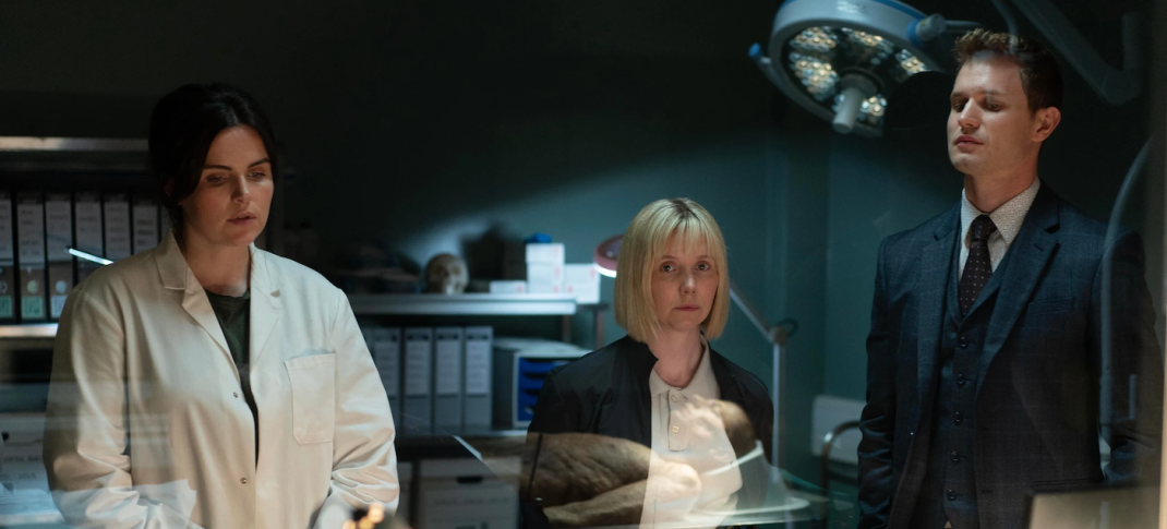 Picture shows: River Wilde (Emer Kenny), Karen Pirie (Lauren Lyle) and DC Jason "Mint" Murray (Chris Jenks) behind a glass wall.